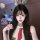 A young woman wears a cute headband with bunny ears, paired with a stylish white top and red tie, embodying a playful schoolg...