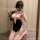 Woman kneeling in mirror selfie wearing sugar island black lace qipao lingerie set with sheer pink bow top and garter details...