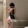 Woman wearing black sugar island lace qipao lingerie with bow detail, sheer thigh-highs, and fluffy trim.