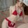 Woman wearing a red sultry sheer -style strapless lingerie set with white lace trim and bows, posing on a bed.