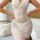 Woman wearing luxury summer lace sleepwear set with sheer floral cami and midi skirt, posing by bed in soft light.