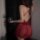 Woman in red lace bodysuit with sheer mesh, low-cut bust, and cut-outs, holding wine glass.