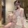 Woman wearing a white sheer lace bodysuit with floral embroidery and a matching robe, posing in a bathroom.