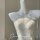 White sheer lace bodysuit with floral embroidery and pearl necklace on mannequin.