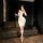 Woman in white bodycon dress holding wine glass, wearing lanyard with badge — summer yang seductive lingerie for women.