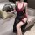 Woman in black sheer cheongsam lingerie with red trim and high slit, holding a fan.