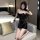 Woman wearing black suoqing fetish leather bondage bodysuit, posing on bed with choker and chains, sexy role play outfit.