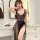 Woman wearing black suoqing lace mesh sleepwear with deep v-neck and sheer panels in a modern bathroom.