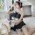 A woman poses wearing a black and white cat-themed sheer maid costume, featuring ruffled details and an open-crotch design, s...