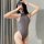 A woman poses in a sleek gray bodysuit, highlighting its form-fitting design and open-crotch style. the smooth fabric accentu...