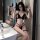 Woman modeling black suoqing sexy lingerie set with cut-out bralette, thong, and garter in bathroom.