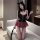 A woman poses wearing a black mirror-finish bustier with lace-up details, paired with a red plaid mini skirt. she accessorize...