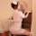 A woman wearing a pink nurse costume sits gracefully by an antique piano, exuding elegance and charm. the outfit features a f...