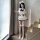 A stylish young woman poses on stairs wearing a cute sailor-themed cosplay outfit. the ensemble features a white top with ruf...