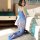 Woman kneeling on bedroom floor wearing blue lace bodysuit with sheer mesh tights, open-crotch design, backless style.