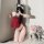 Woman in red suqing vintage lace bodysuit with embroidered tie-straps, posing on white rug beside pink roses.