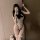 A stylish individual poses with a smartphone, wearing a chic white bodysuit paired with a black bow tie. the outfit features ...