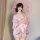 A woman elegantly poses holding a delicate pink parasol, wearing a sweet and seductive yukata robe adorned with floral prints...