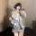 A woman poses with a smartphone, wearing a floral-patterned yukata robe. the light blue satin fabric features a large bow det...