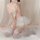 Woman kneeling in sweet & spicy sheer lace lingerie set with floral mesh bra, ruffled panty, and white thigh-high stockings.