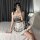 A person wearing a plaid maid costume dress with lace details and bunny ears, sitting on a bed while taking a selfie. perfect...