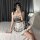 A person wearing a plaid maid costume dress with lace details and bunny ears, sitting on a bed while taking a selfie. perfect...