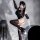 Cosplayer posing with sword, wearing ultra-thin bodysuit, sheer stockings, and open-crotch design.