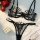 Sheer black lace lingerie set with delicate straps, styled with red roses and pearls for a sensual, romantic look.