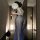 Woman in vintage chinese-inspired lace cheongsam lingerie set with sheer mesh skirt, holding a fan in a hallway.