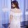 Woman wearing white off-shoulder lace nightgown with floral embroidery, sheer fabric, elegant back view.