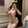 Woman wearing white bunny costume bodysuit with open cups, pink bow, lace detailing, and thigh-high stockings for cosplay.
