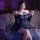 Woman in navy lace bodycon skirt set with sheer sleeves, posing on bed with rose petals for date night.