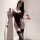 Woman wearing black lace bodysuit with sheer backless design, paired with matching stockings, holding a decorative wand.