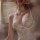 Woman wearing a white low-cut push-up lace chemise set with sheer bralette and matching thong, featuring satin sleepwear deta...