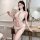 Woman wearing white lace bodysuit with push-up design, holding feather wand in elegant room setting.