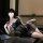 Woman lounging on a table in a sheer black lace sleepwear set with a chest-baring camisole and shorts.