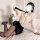 Woman in white blouse and black skirt posing on bed, wearing sheer sleeves and tie, styled as seductive ol secretary costume ...