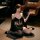 Woman in black luxury lingerie set with gold accents, posing elegantly on floor with feather fan — sensual, mature, alluring ...