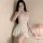 A woman poses with a smartphone, wearing a beige backless ice silk bodycon dress. the high-elastic slip dress features adjust...