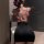 Woman wearing sheer floral lace bodysuit with halter neck and black mini skirt, back view.