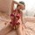 Woman wearing red lace halter bodysuit with sheer mesh panels and ruffled details, posing seductively on a bed.