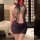 Woman wearing a black lace secretary costume with halter neck and sheer mesh skirt, featuring a red rose accessory.