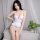 Woman modeling white open-crotch lingerie set with ruffled hem and deep v-neck, inspired by uniform style for bold confidence...