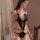 Woman wearing qqny black lace open-cup bodysuit with sheer panels and bow details, elegant sleepwear set.