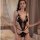 Woman wearing qqny black lace open-cup bodysuit with sheer panels and bow details, styled as sexy sleepwear in bedroom settin...
