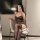 Woman wearing a sheer black mesh nightgown with adjustable drawstrings, posing in a stylish indoor setting.