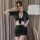 Woman wearing black sheer office secretary outfit with tied crop top and mini skirt, posing indoors for date night or role pl...
