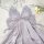Lavender ice silk sleep dress with bow detail and backless cutout, styled on fluffy white rug with pearls and flowers.