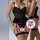 Woman modeling black lace lingerie set with underwire push-up bra and matching thong, featuring sheer panels and garter strap...