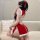 A woman poses on a couch wearing a festive red christmas-themed cheongsam outfit. the dress features sheer bust design, white...
